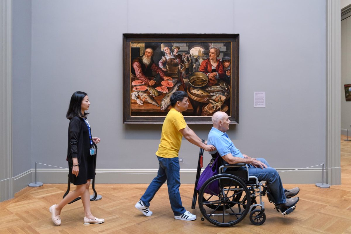 Companion pushing a wheelchair user through a museum gallery